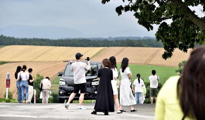 Khách du lịch giúp ảnh giữa đường ở Biei, Hokkaido, bất chấp một chiếc xe hơi đang lao tới. Khách du lịch giúp ảnh giữa đường ở Biei, Hokkaido, bất chấp một chiếc xe hơi đang lao tới.